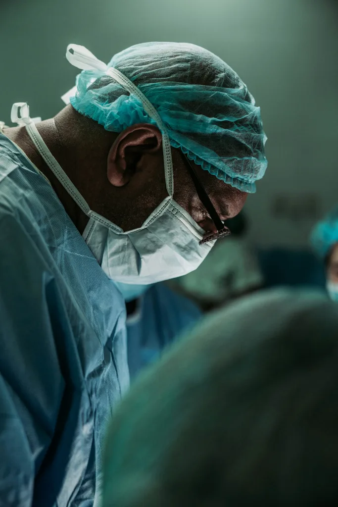 Chirurg mit OP-Haube und Mundschutz konzentriert bei einer Operation