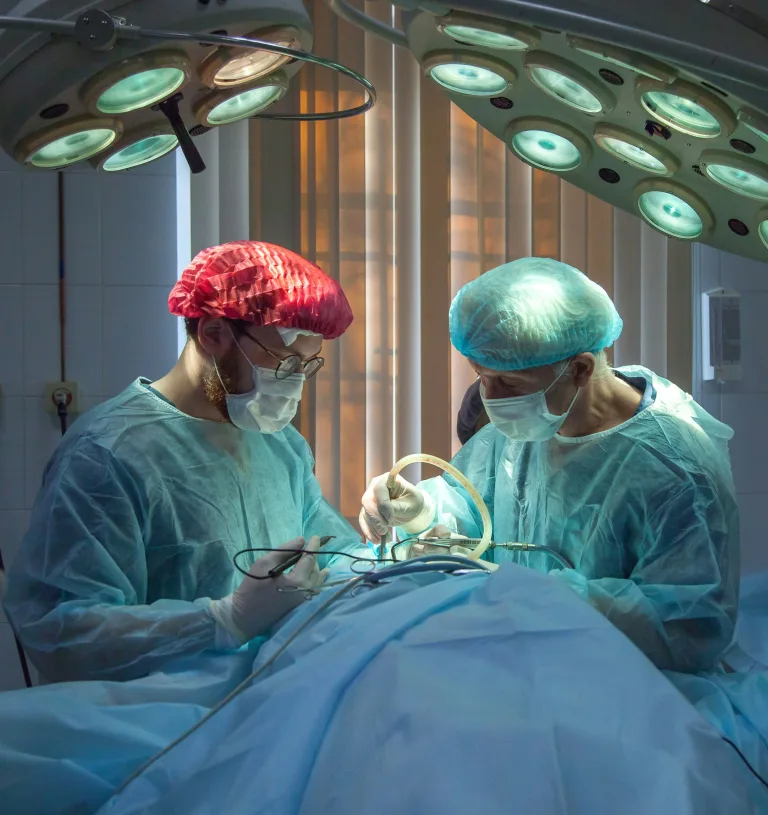 Zwei Chirurgen in OP-Kleidung bei einer Operation unter OP-Leuchten
